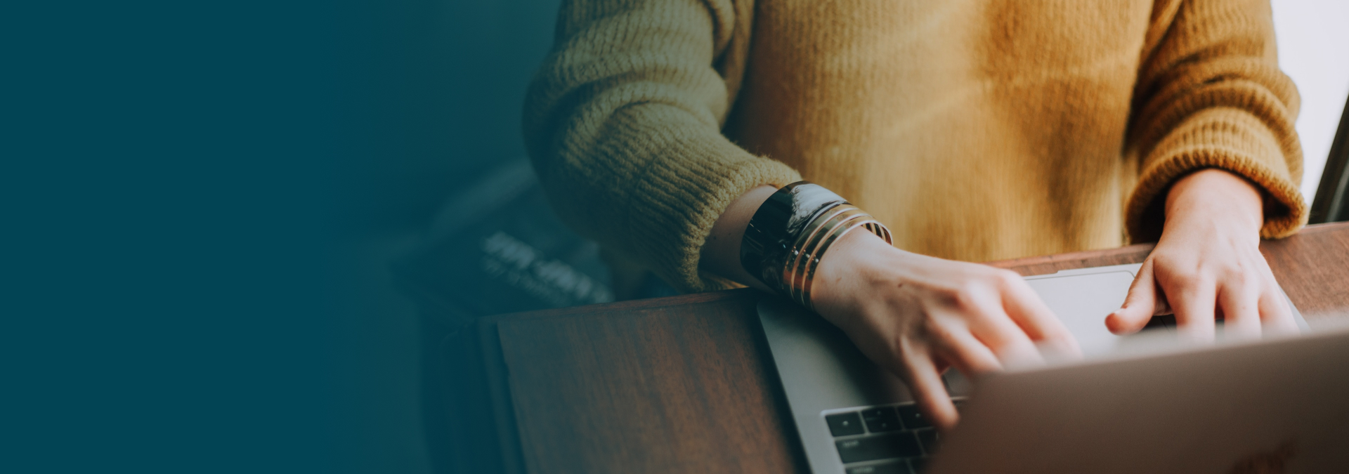 Zoomed in hands using a laptop with a Yellow jumper on